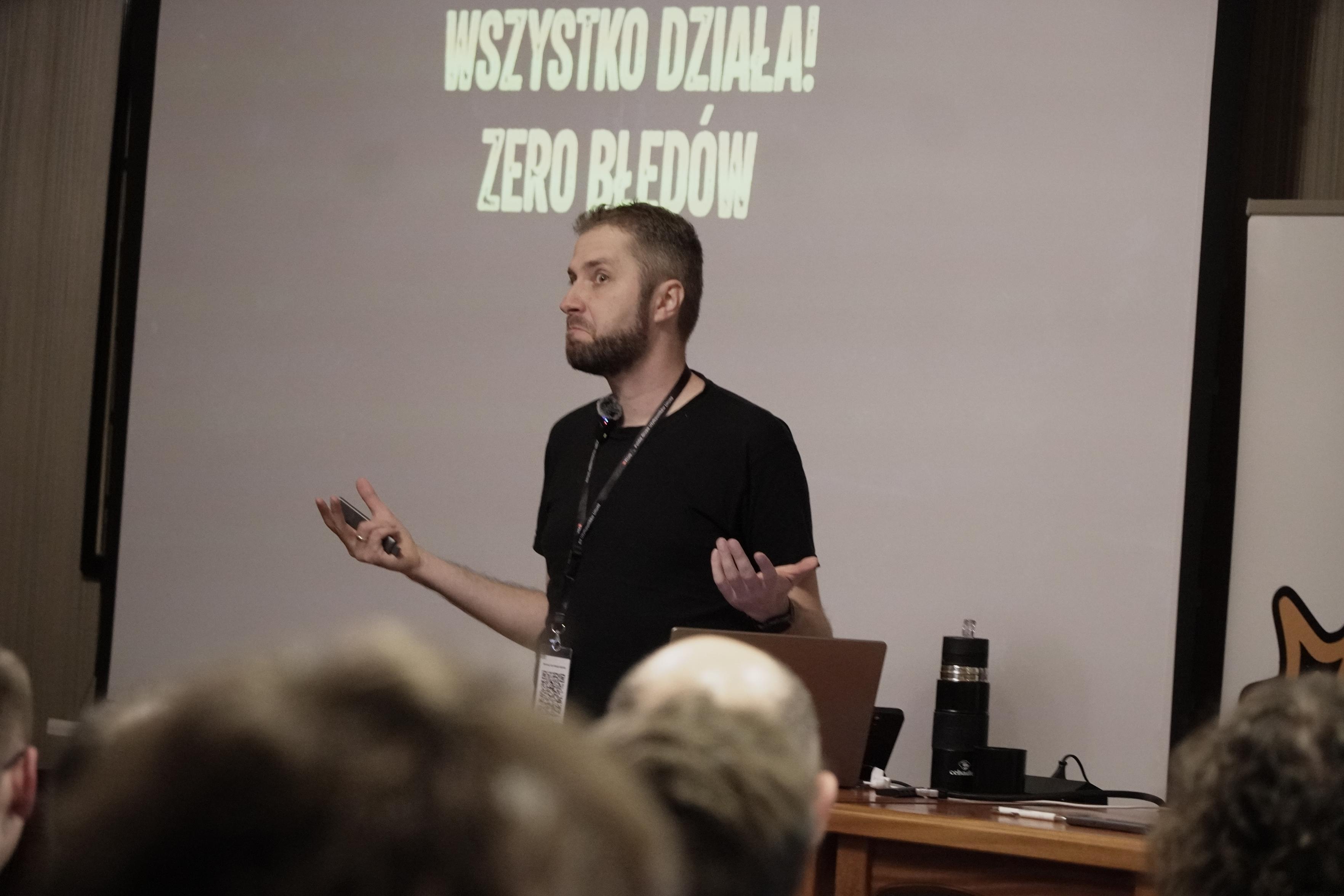 Zdjęcie prelegenta Kuby Mrugalskiego na scenie. 