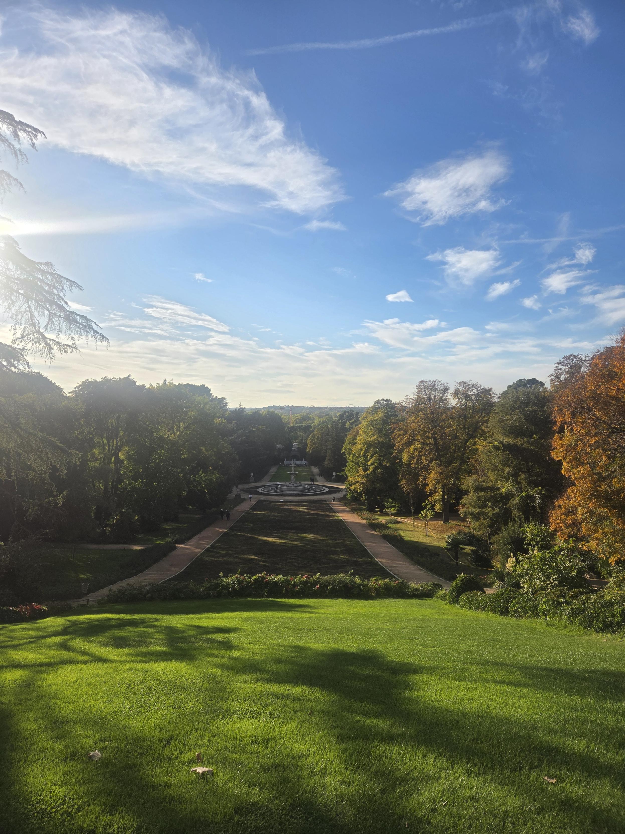 View of a giant fountain in the palace gardens with blue skies and autumn colours in the background