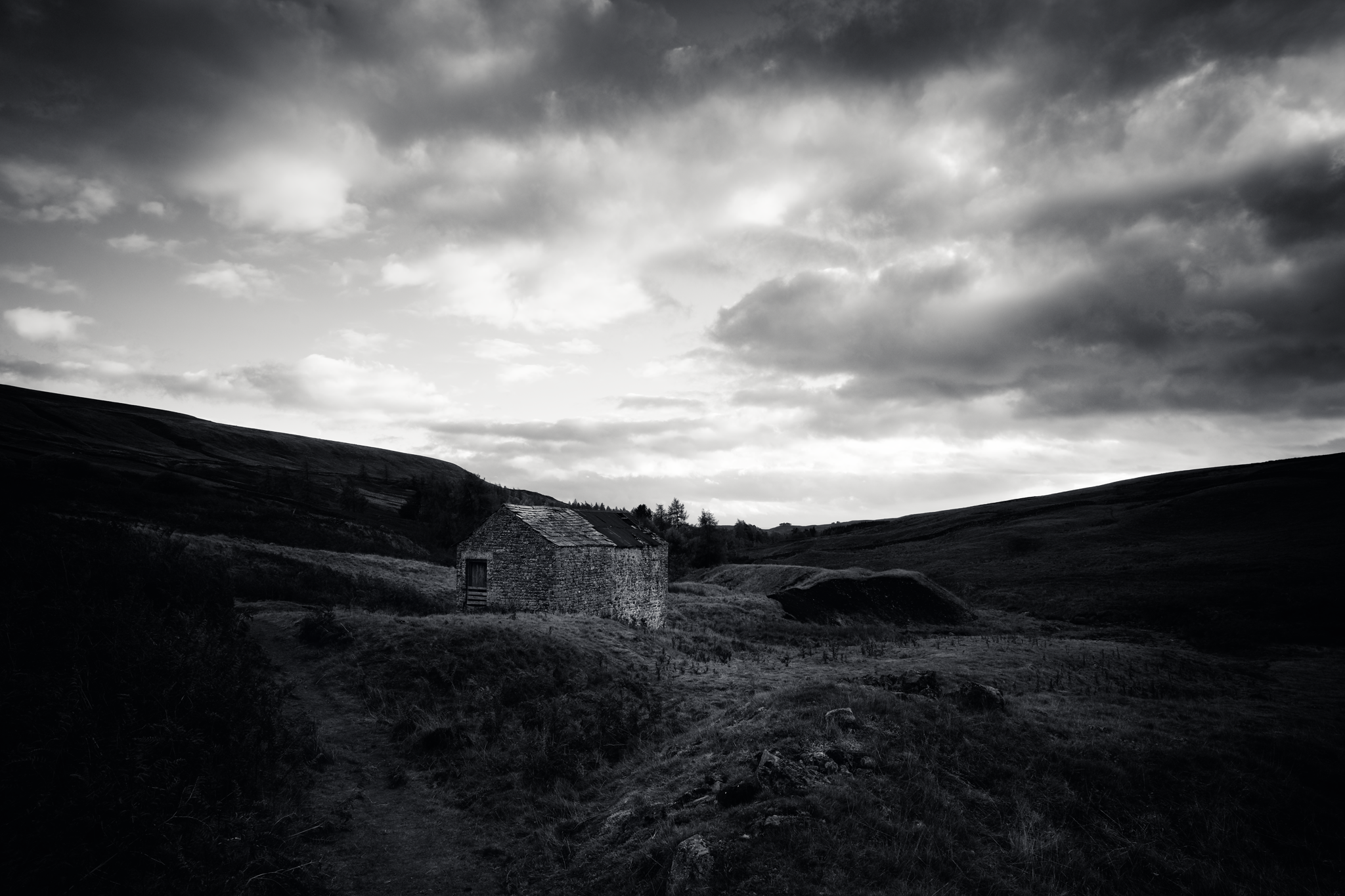 Moody black and white scene, a broken down barn in remote countryside.