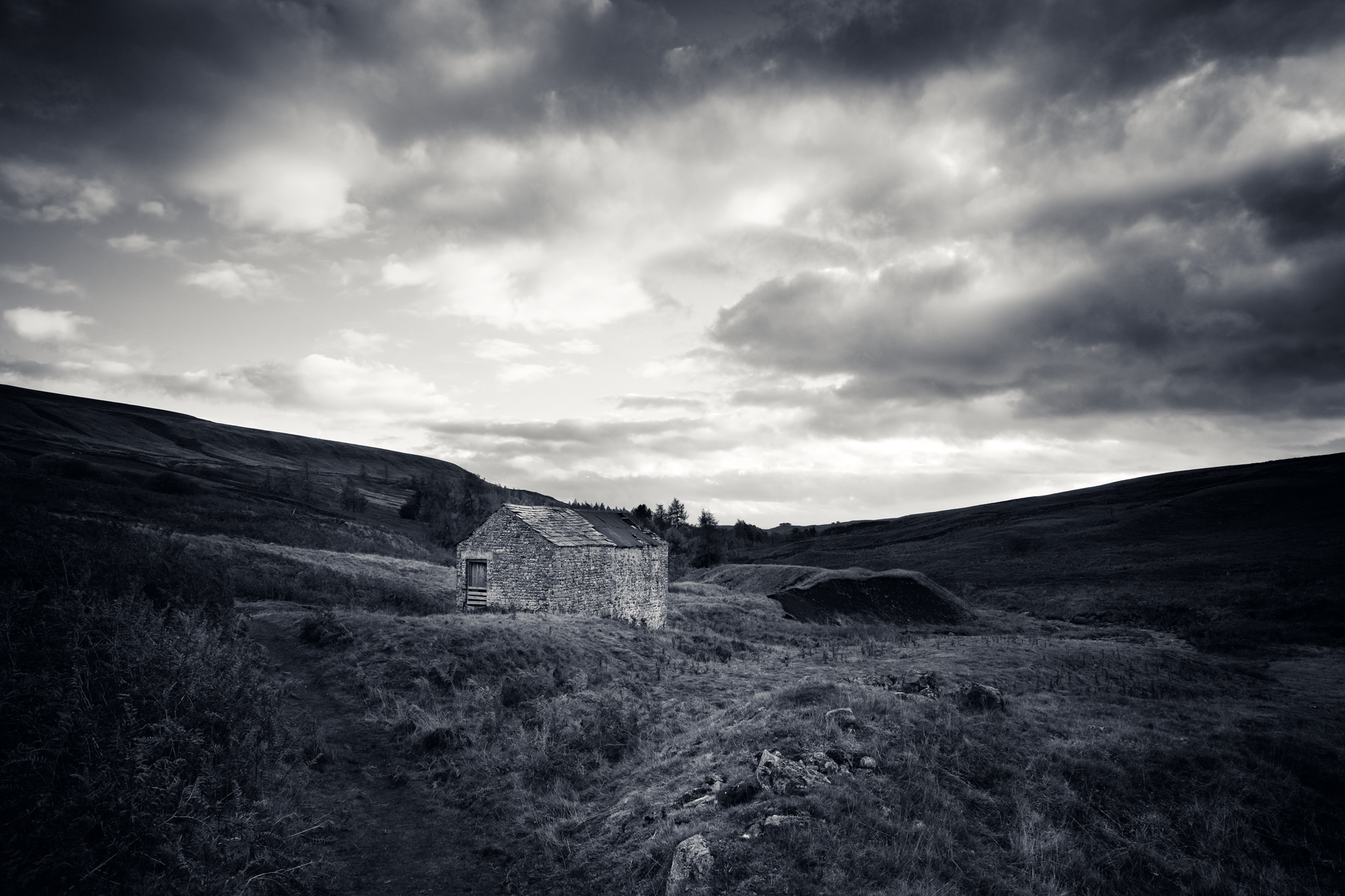 Moody black and white scene, a broken down barn in remote countryside.
