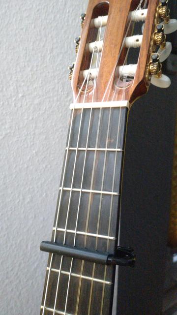 Ein schwarzes Kapodaster am 3. Bund einer Konzertgitarre