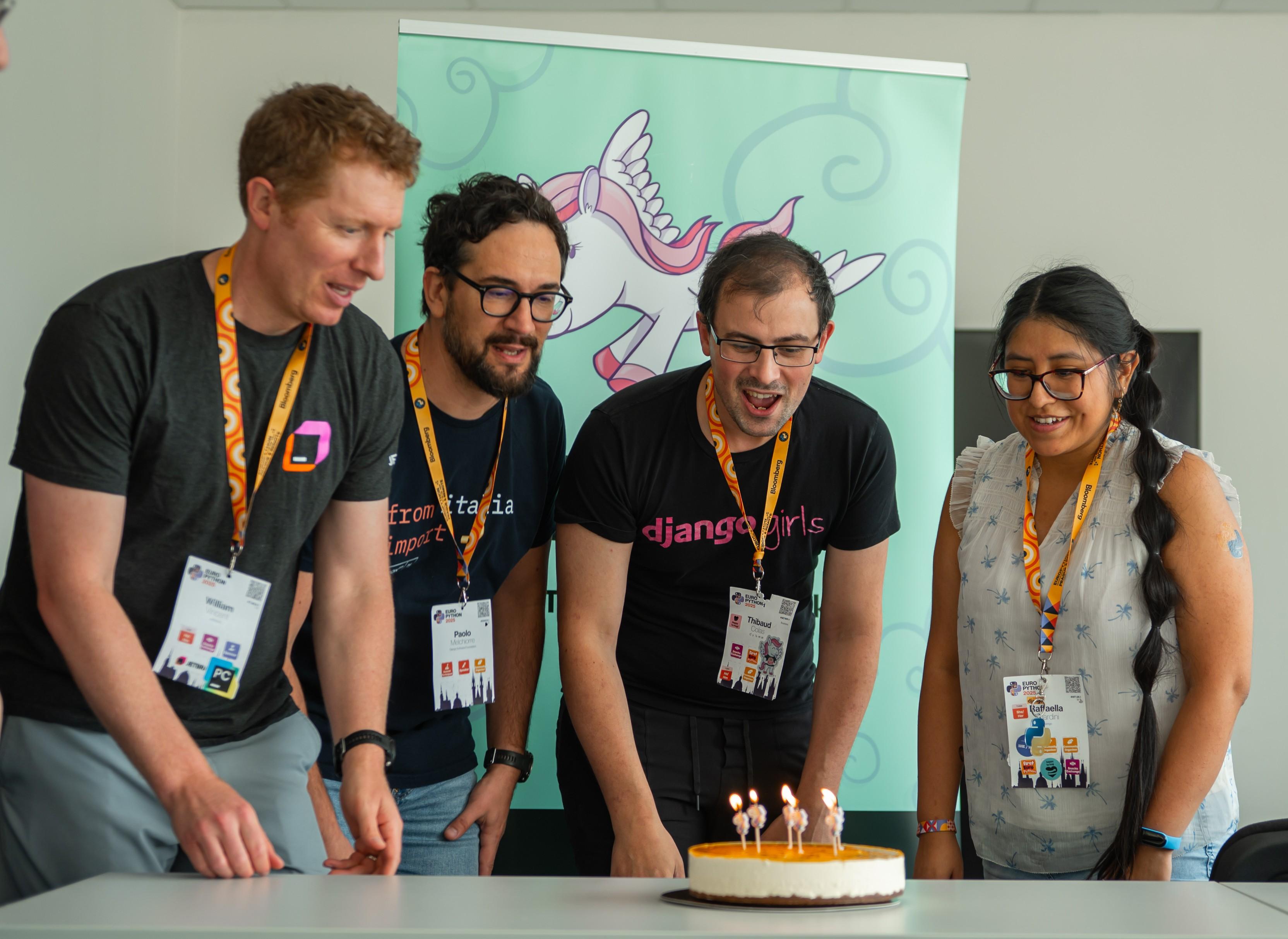 Photo of a small celebration during EuroPython 2025 marking the 20th anniversary of Django. I am blowing out candles on a cake while other Django contributors stand nearby. An official Django banner is visible in the background, capturing a shared and symbolic community moment.