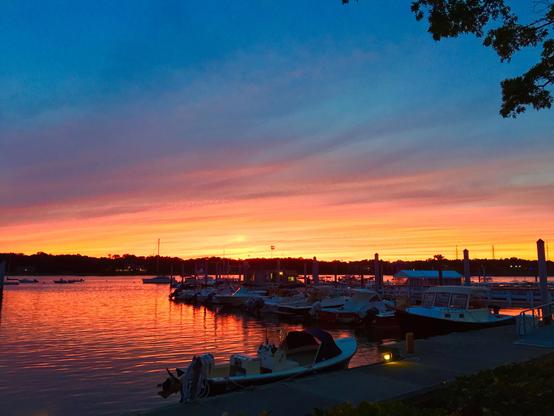A marina with boats docked under a colorful sunset sky.