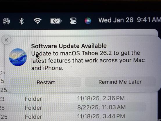Software update notification for macOS Tahoe 26.2 on a Mac screen, with options to restart or remind later.