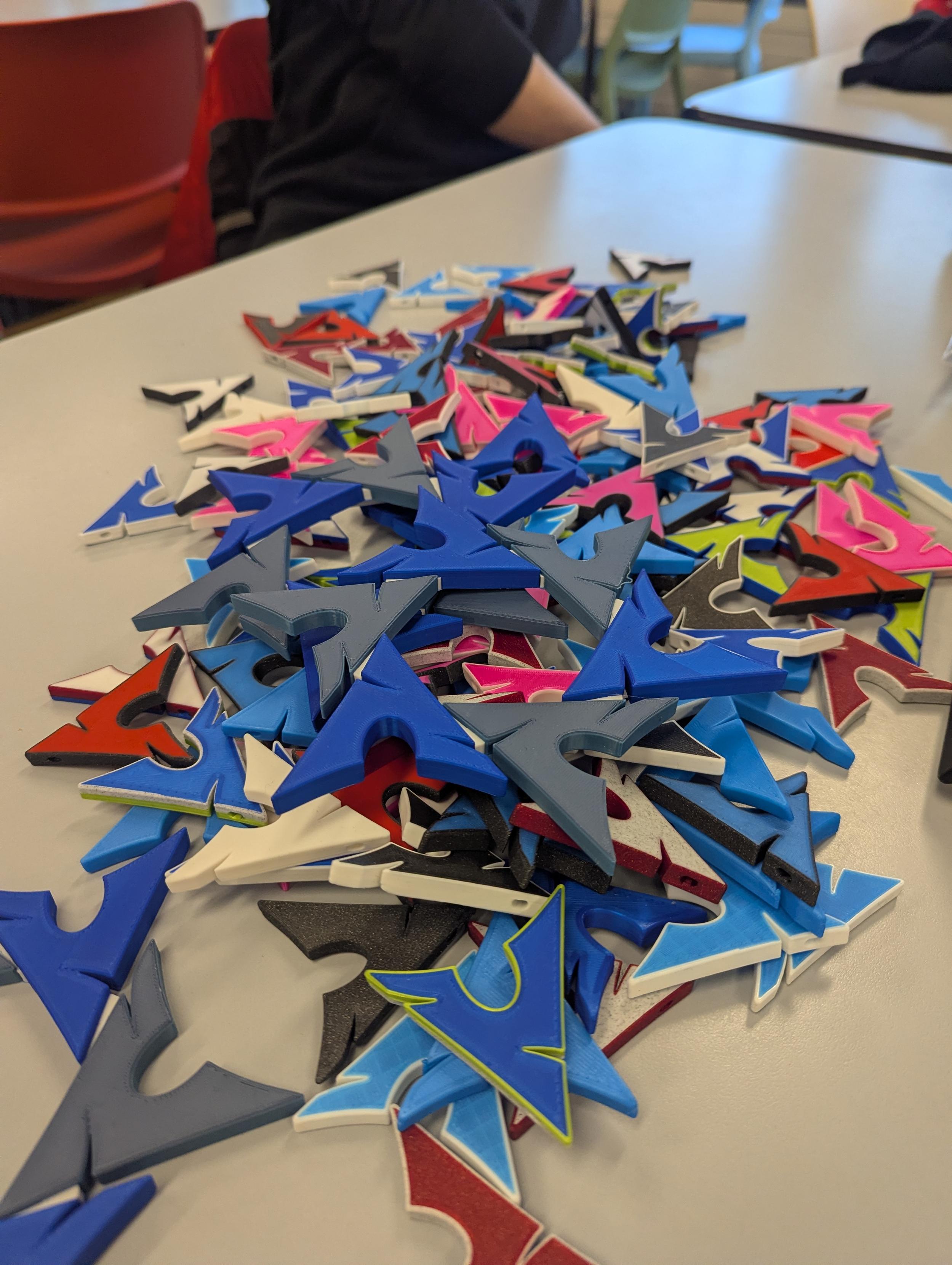 Picture of a table with a lot of 3D printed Arch Linux keychains on top.