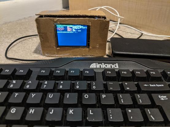 2.4 inch display inside cardboard case with pfetch displayed on a raspberry pi zero w 2