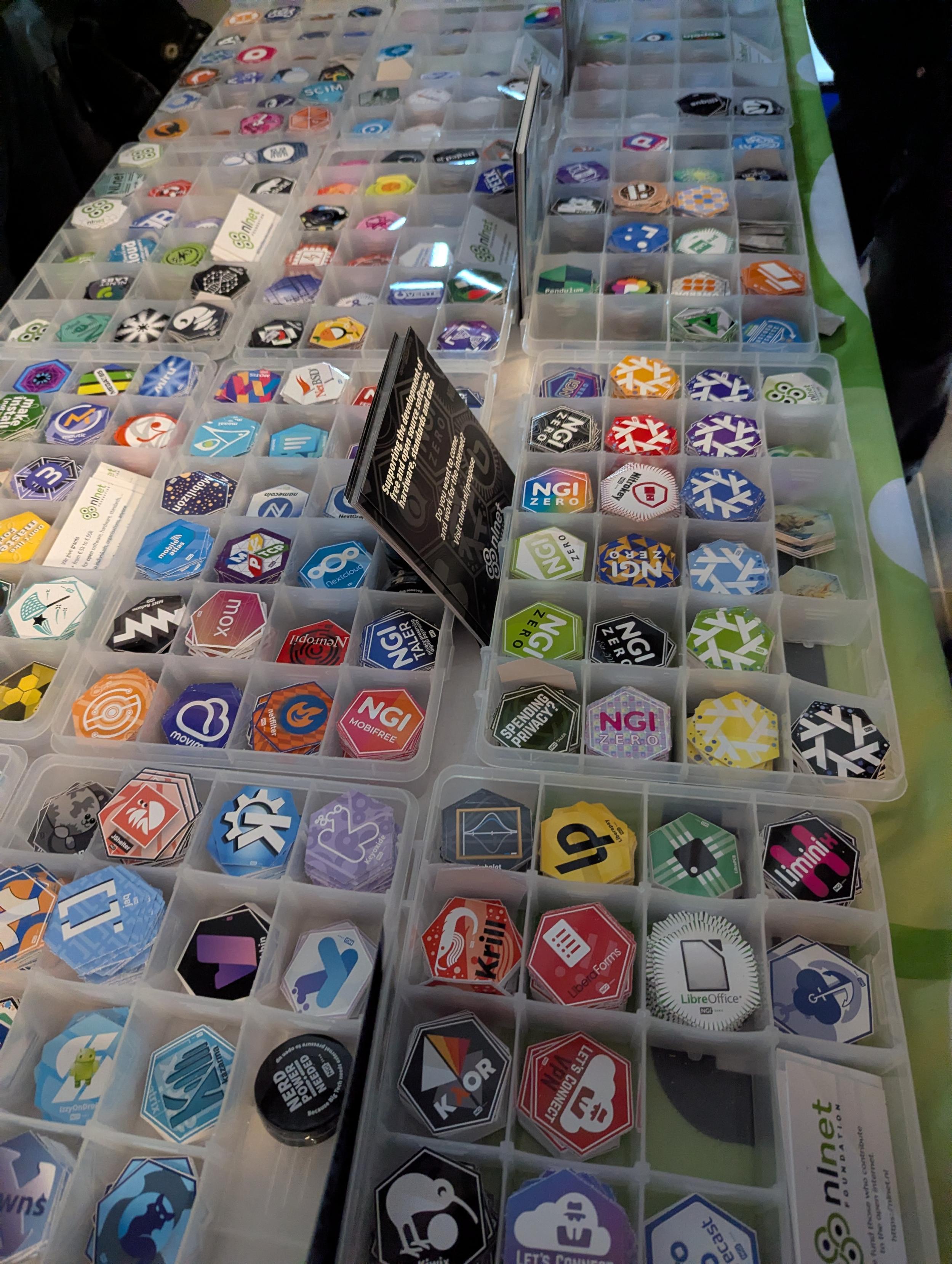 Desks with boxes full of logo stickers sorted in alphabetical order by projects they represent