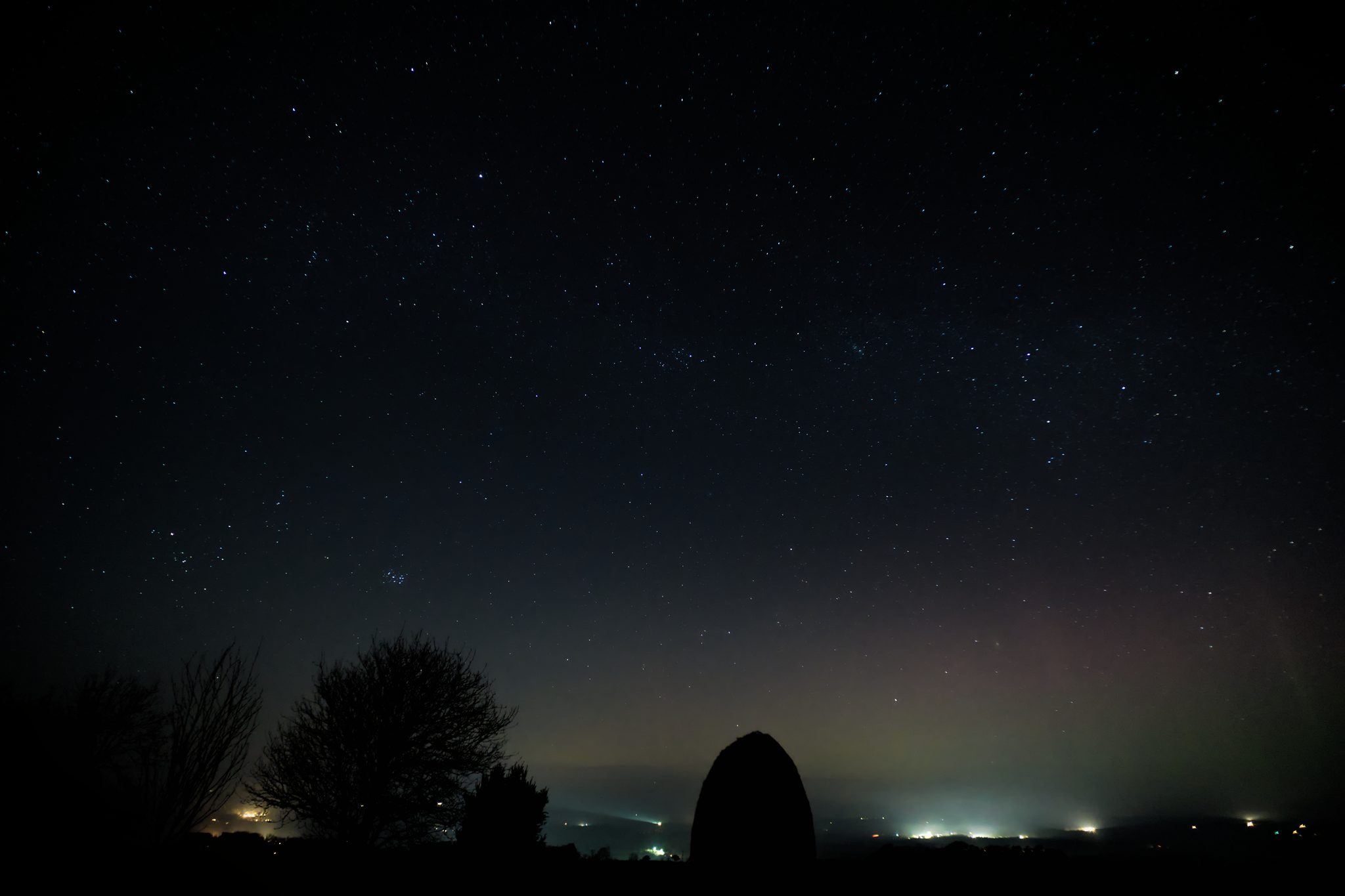 Night sky, with stars, and there's an aurora-like glow, but it might just be lights from nearby farms glowing up through the low mist.