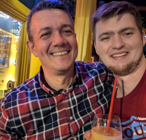 night life selfie with Storm and Serafeim smiling at the camera, Storm is holding a cocktail