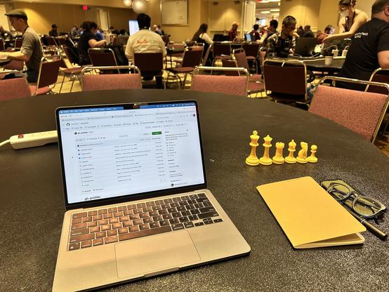 My work setup, with a laptop, notebook, and some chess pieces