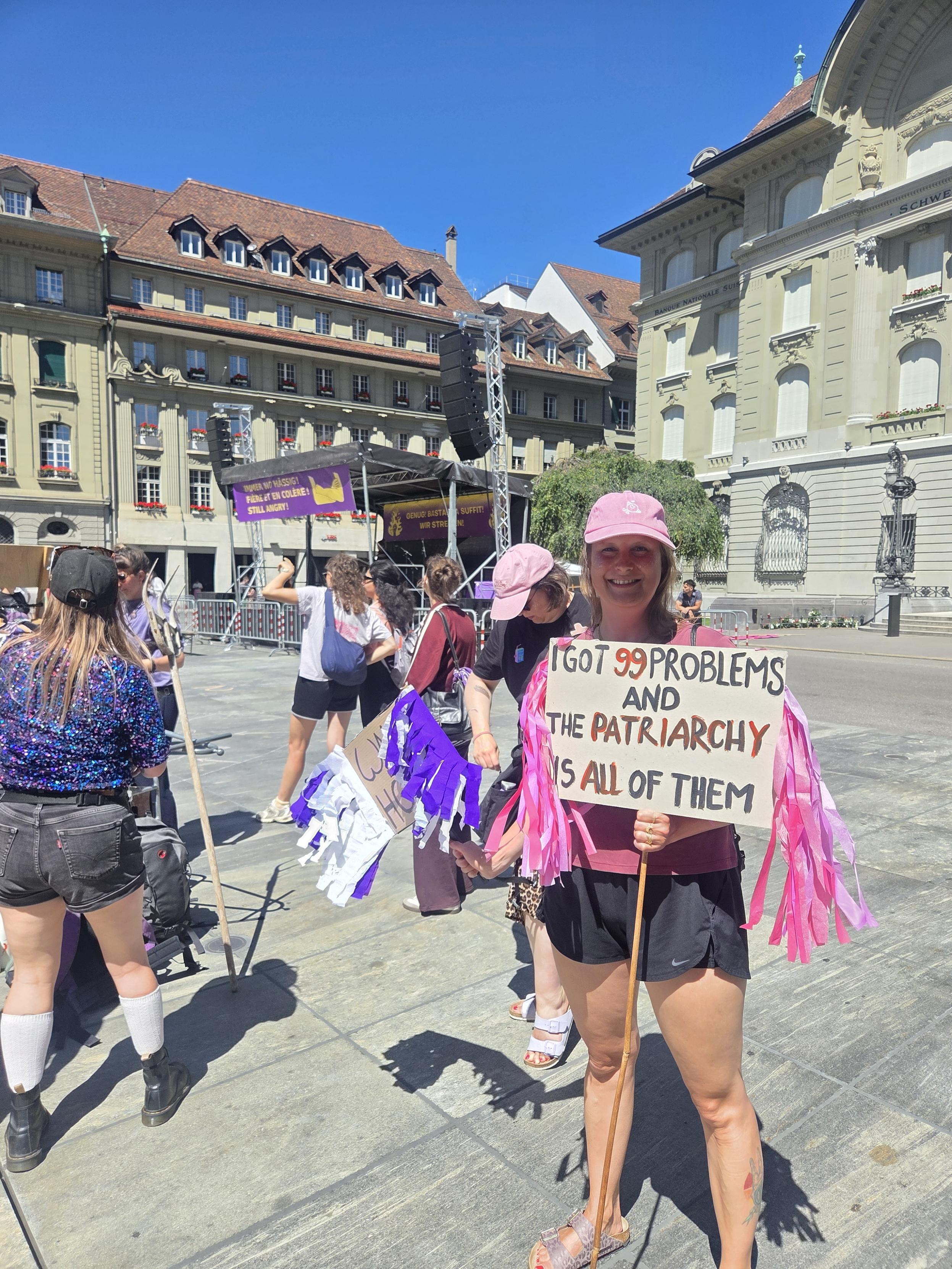 A friendly girlie holding up a sign saying "I've got 99 problems and the patriarchy is all of them"