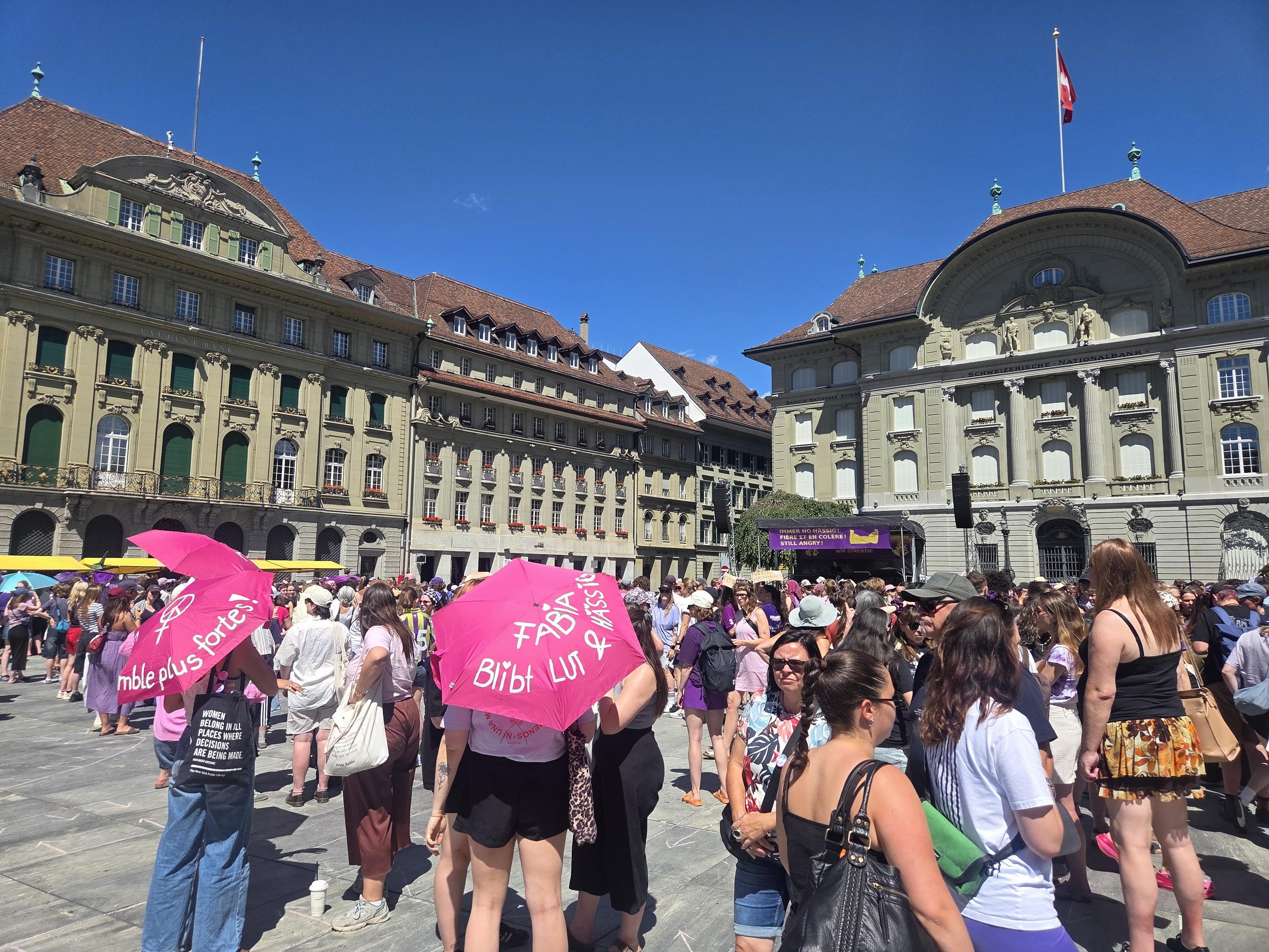 A crowd with pink umbrella's saying something something "more strength" (not sure what it says but it looks awesome)