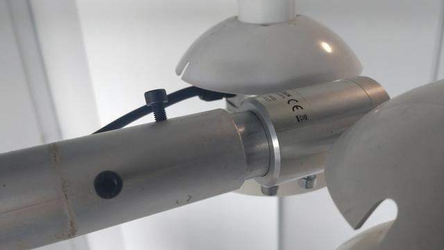 photo of the assembled finished part. A pole from the left has the part stuck into it and fixed with two screws, on the right-hand side there's a Hukseflux NR01 net radiometer (to measure incoming and outgoing short-wave and long-wave radiation) attached