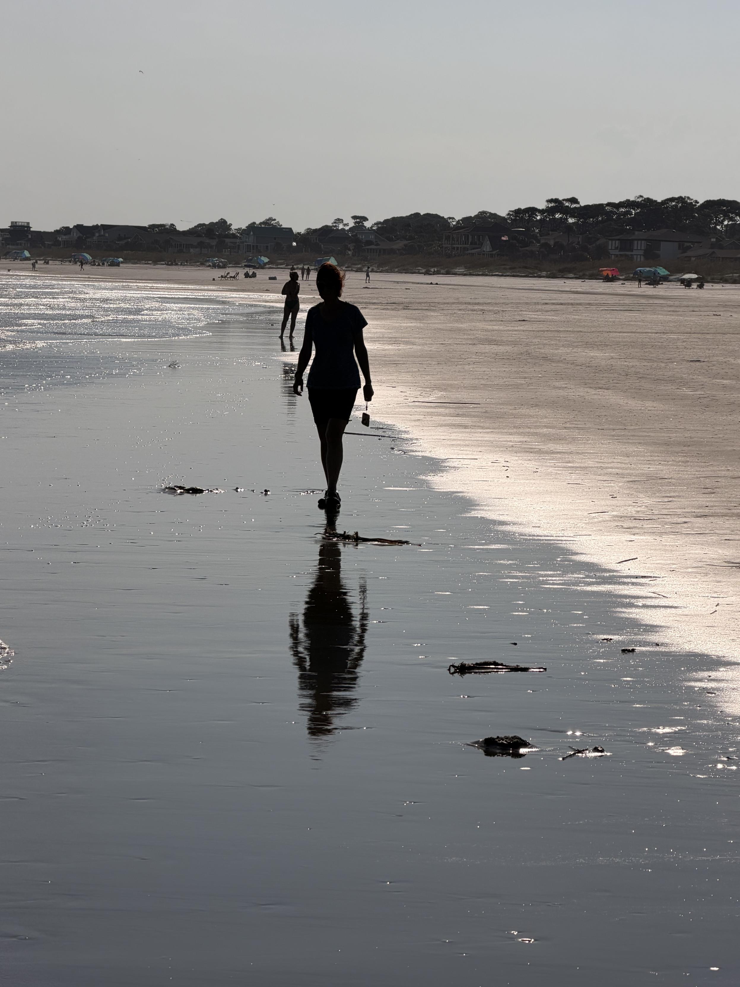 Shadows and reflections of people on wet sand.