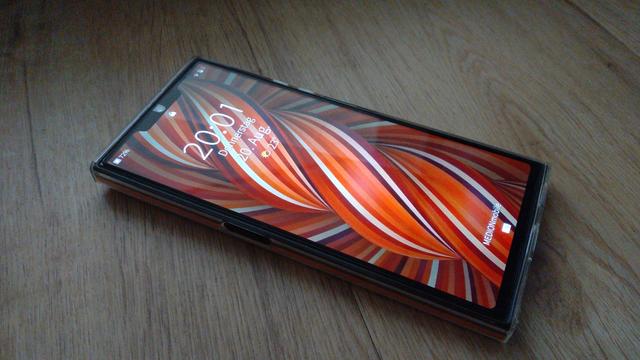 Jolla phone in rubber casing showing lockscreen and red theme