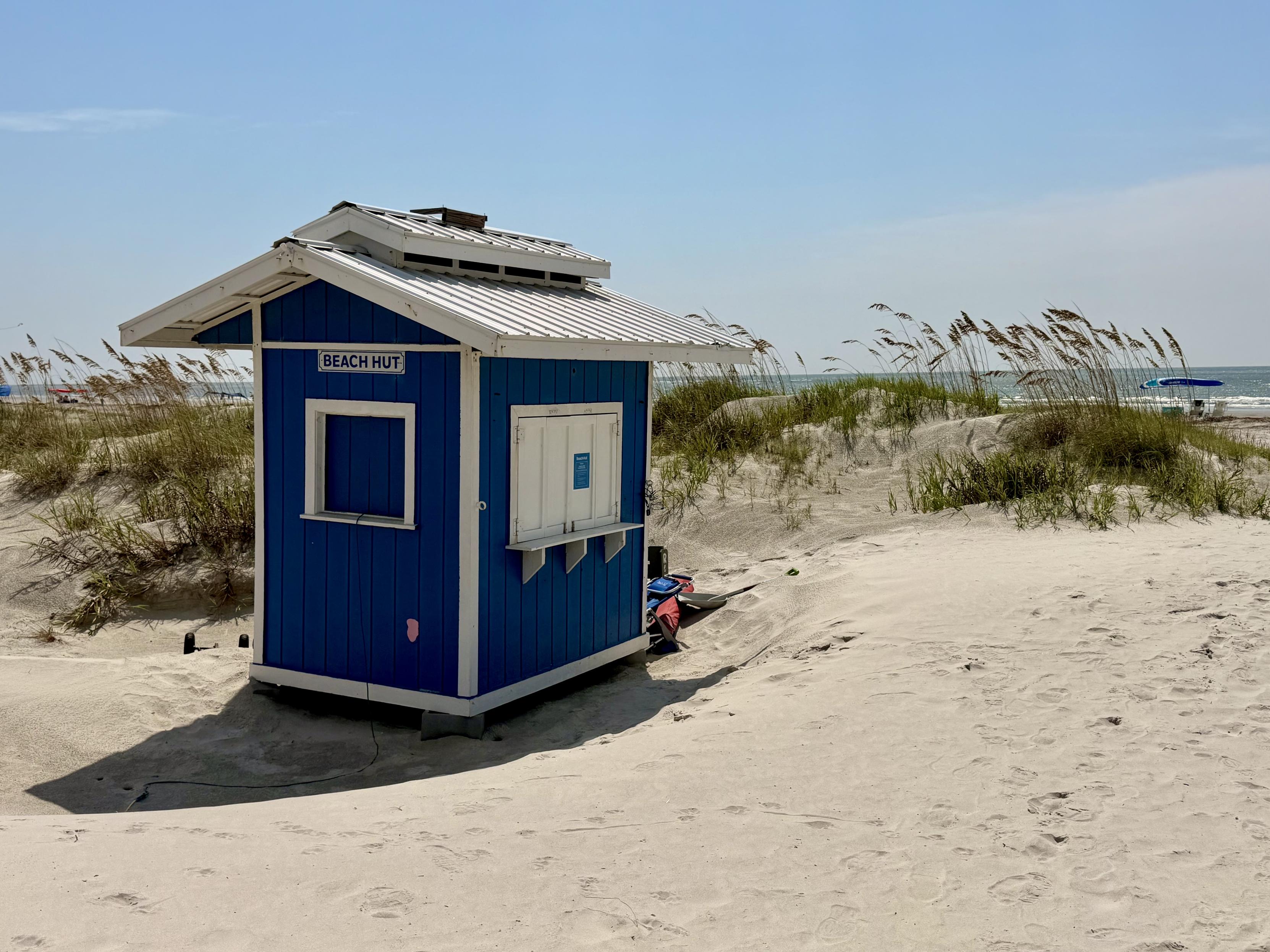 Beach hut in the dunes slowly becoming buried by blowing sand.