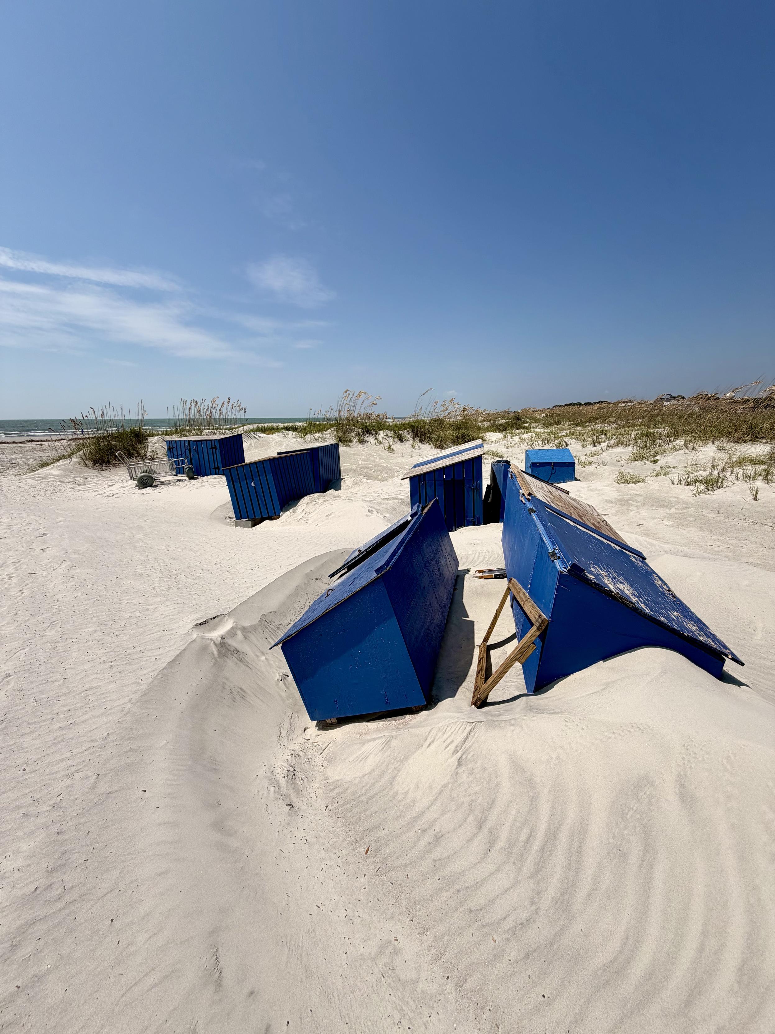 Storage bins half buried in sand dunes.