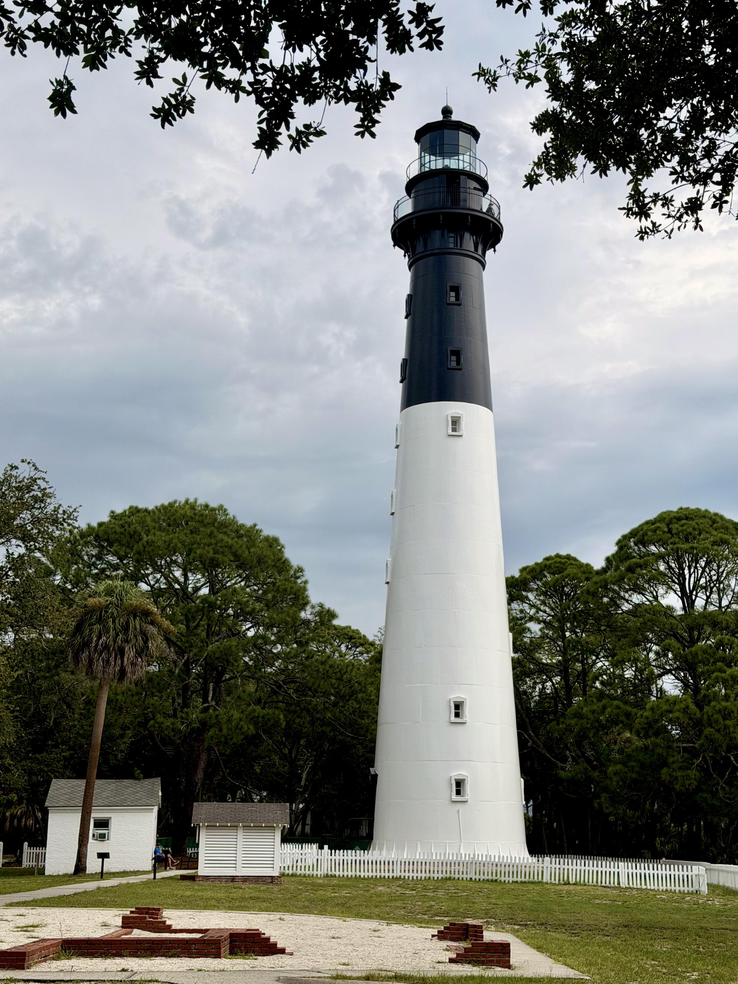 Black and white lighthouse among maritime forest.