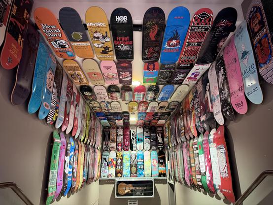 Colorful skateboard decks with band art cover walls around a guitar display in a corner.