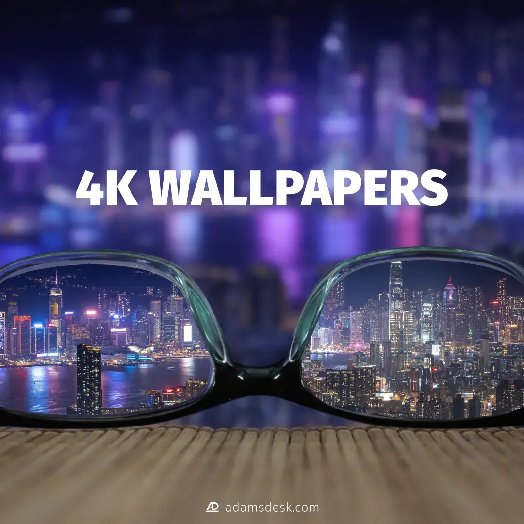 A blurred night city skyline covers the background with glasses placed upside down in the foreground along with a bold white title above of '4K Wallpapers'. Through the lens of the glasses shows a clear vision of the city skyline.