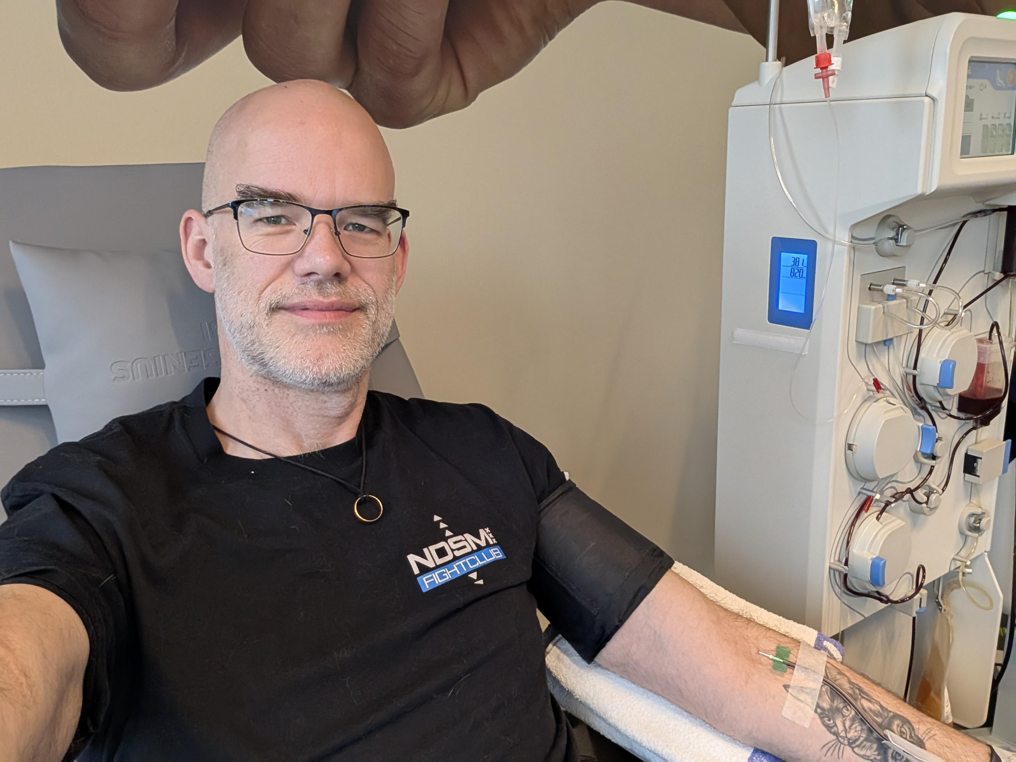 Sybren in a black NDSM Fightclub shirt, with a plasma machine on the right and a needle in his arm.