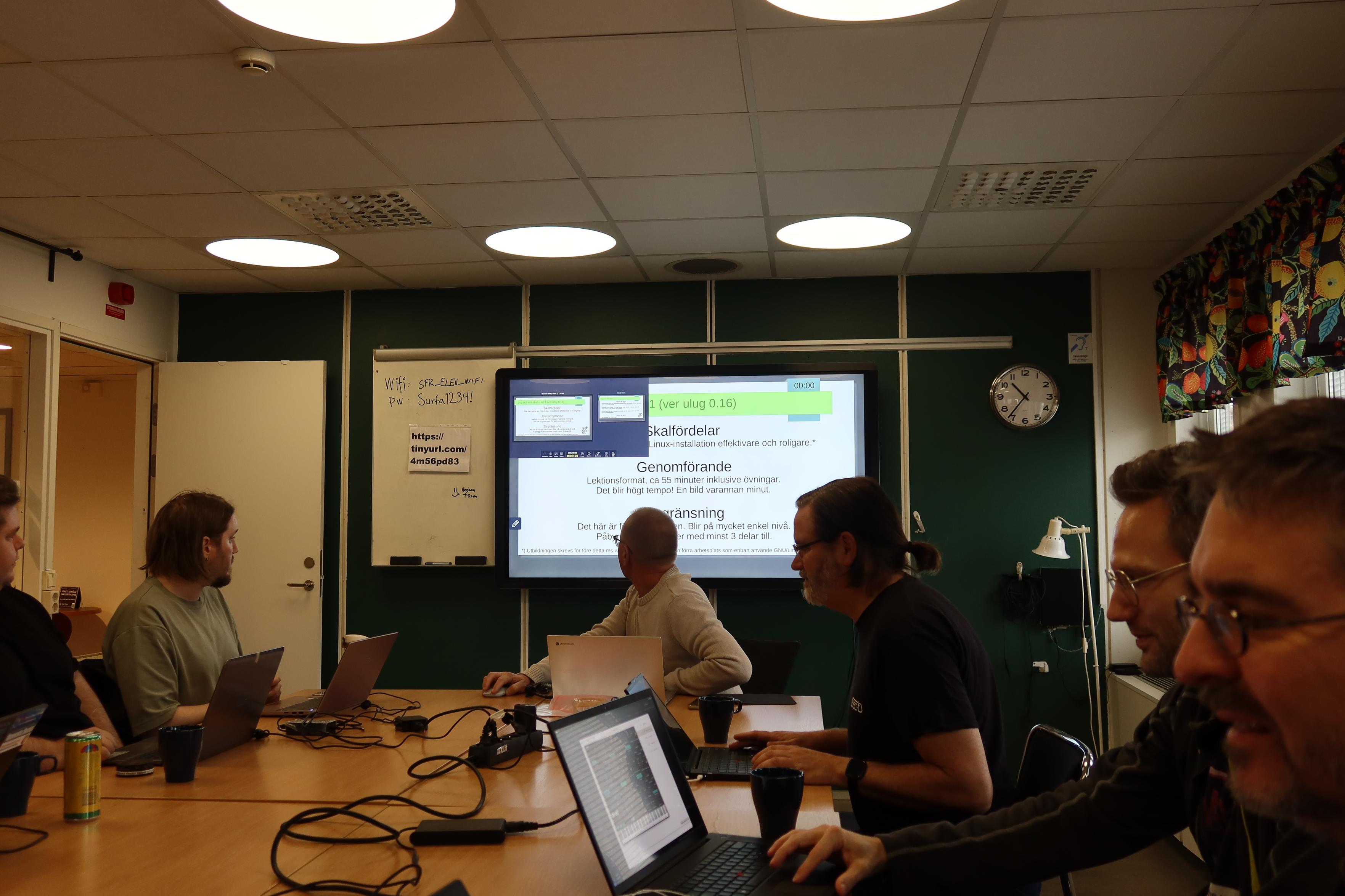 Room with people using laptops, presentation on a bigscreen
