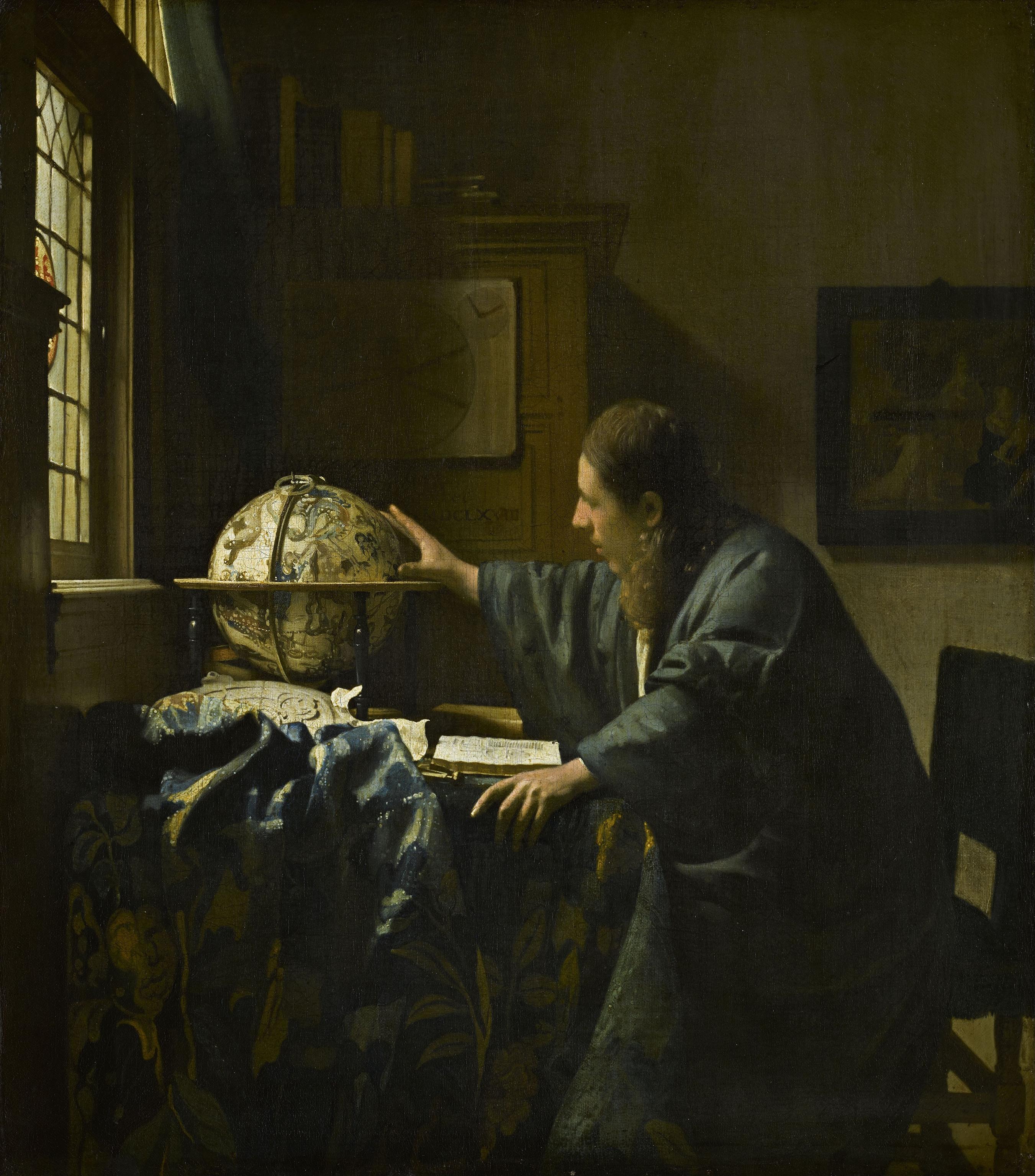Man at a desk, reaching with his right hand towards a globe. The globe has a celestial map on it.