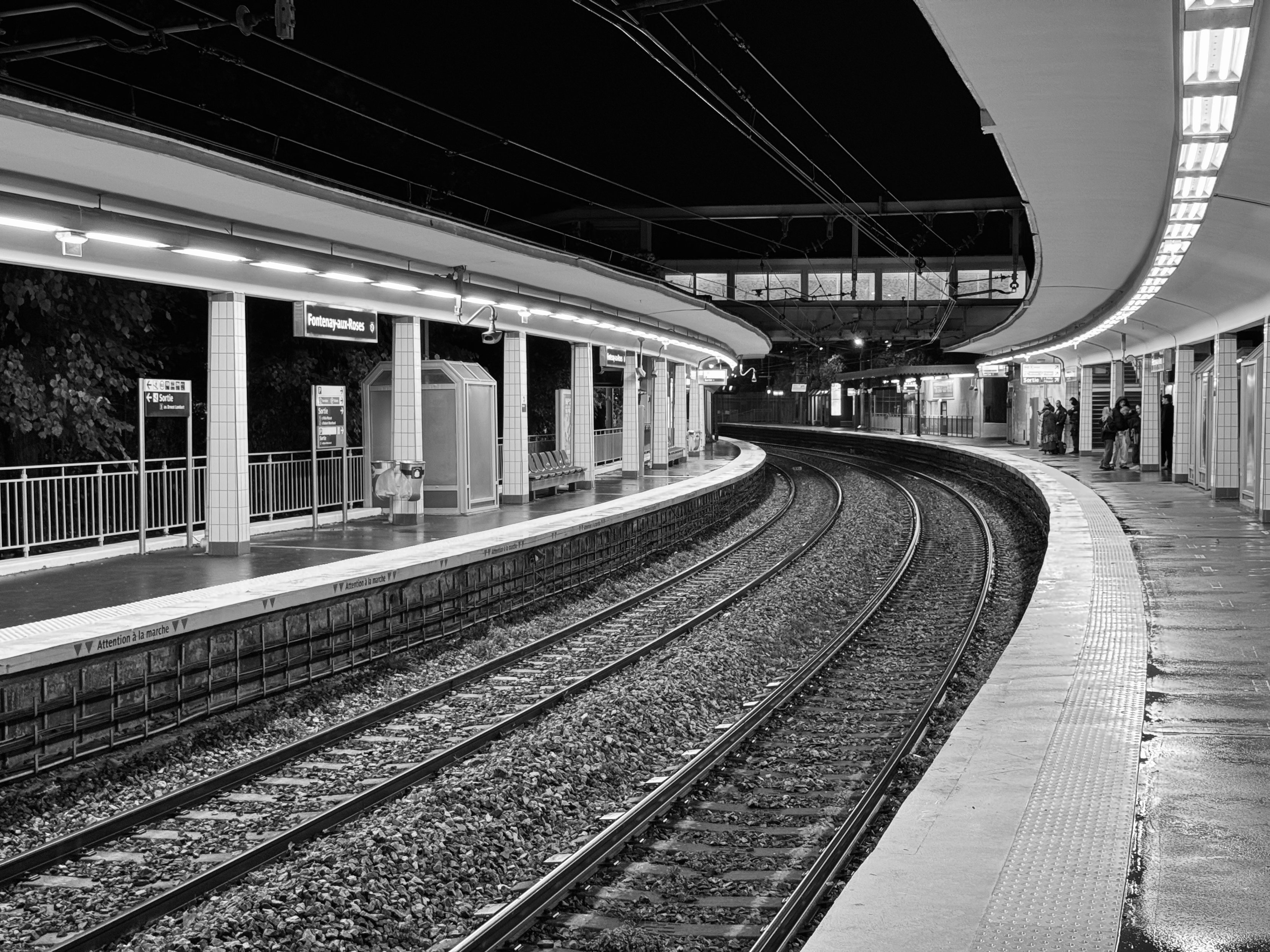Curved train tracks between two platforms illuminated by neon lights, in Fontenayx aux roses