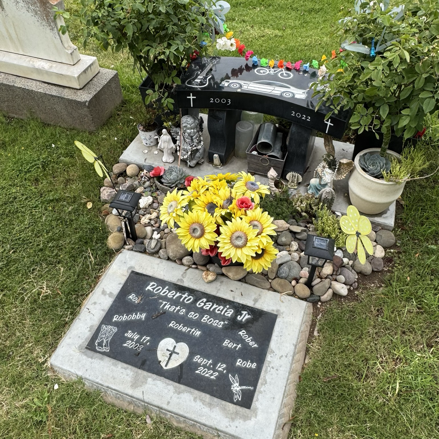 grave of Roberto Garcia Jr.: vibrant, with youthful ephemera & live lizard on headstone.