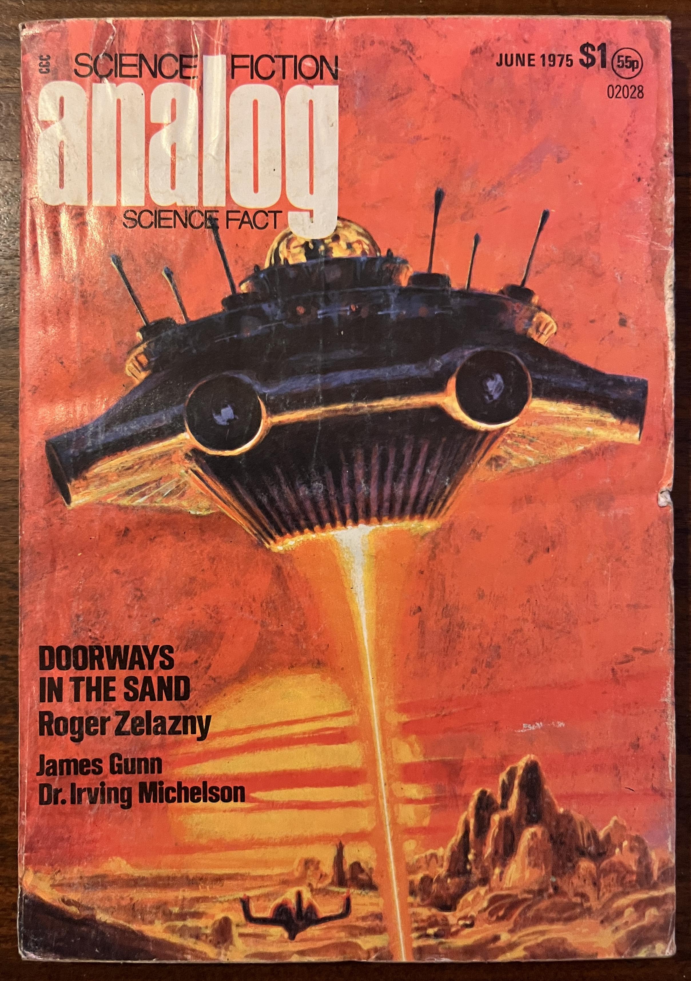 Photograph of the front cover of Analog Science Fiction And Science Fact, from June 1975. It's not in great condition, but it's 50 years old and not falling apart so it's doing better than me. The cover art shows a flying saucer over a rocky desert landscape with a sun low on the horizon and partially obscured by clouds. Everything is in reds and oranges indicating sunset, except the space ship, the shadowed parts of which, facing towards us, are blue/purple. Another ship - or possibly a rotor-c