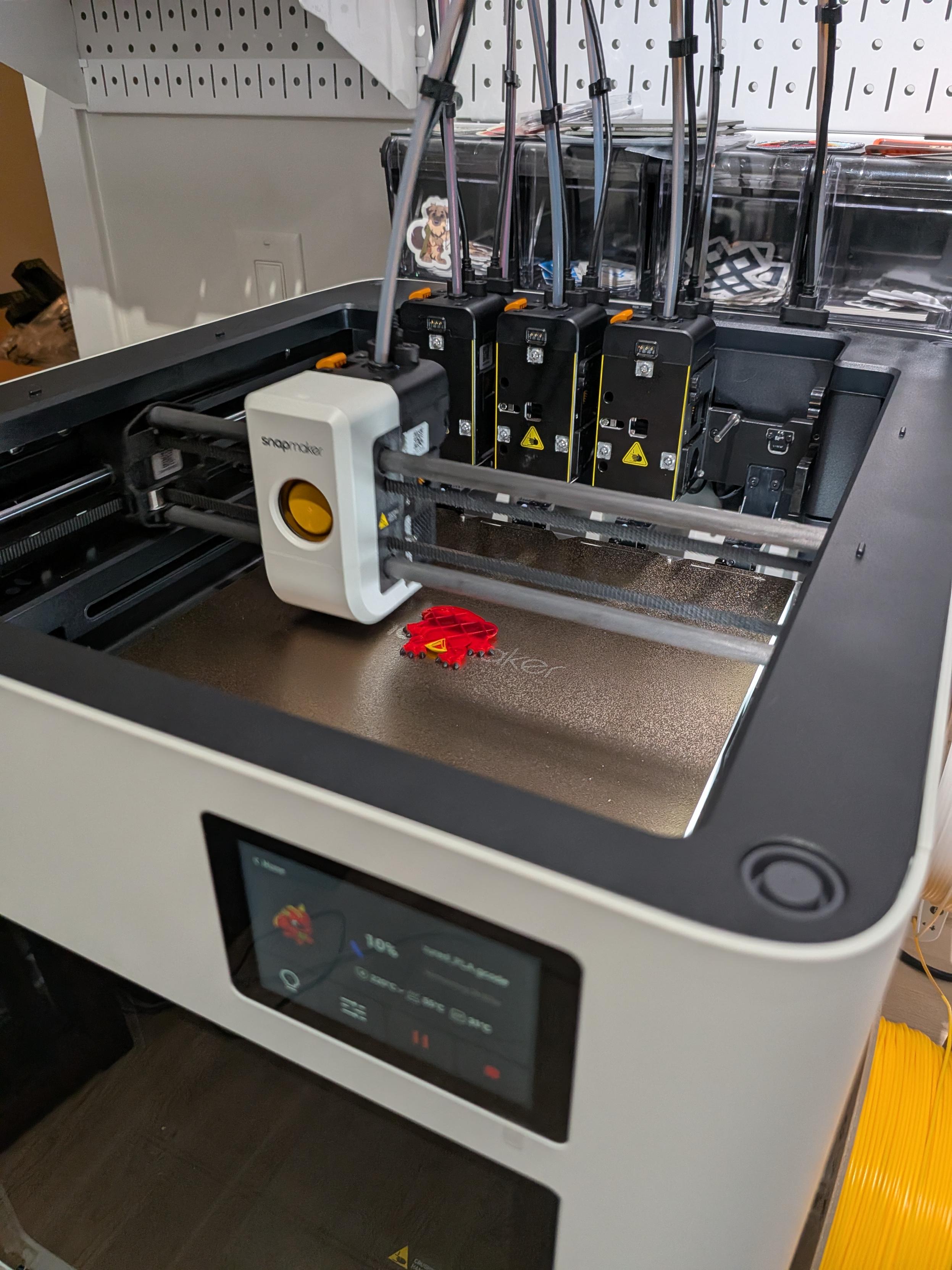 Filament printer in the middle of printing a dragon multi-color print.